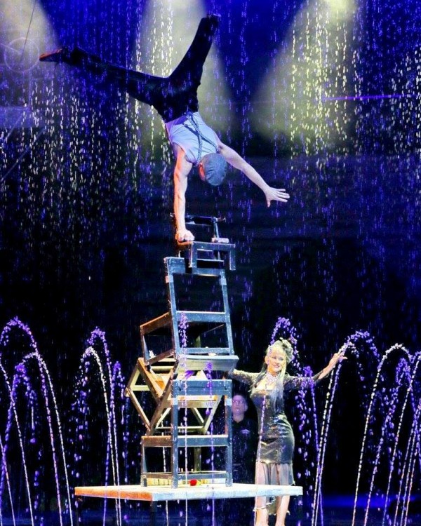 Cirque Italia acrobat balancing on a chair upside down